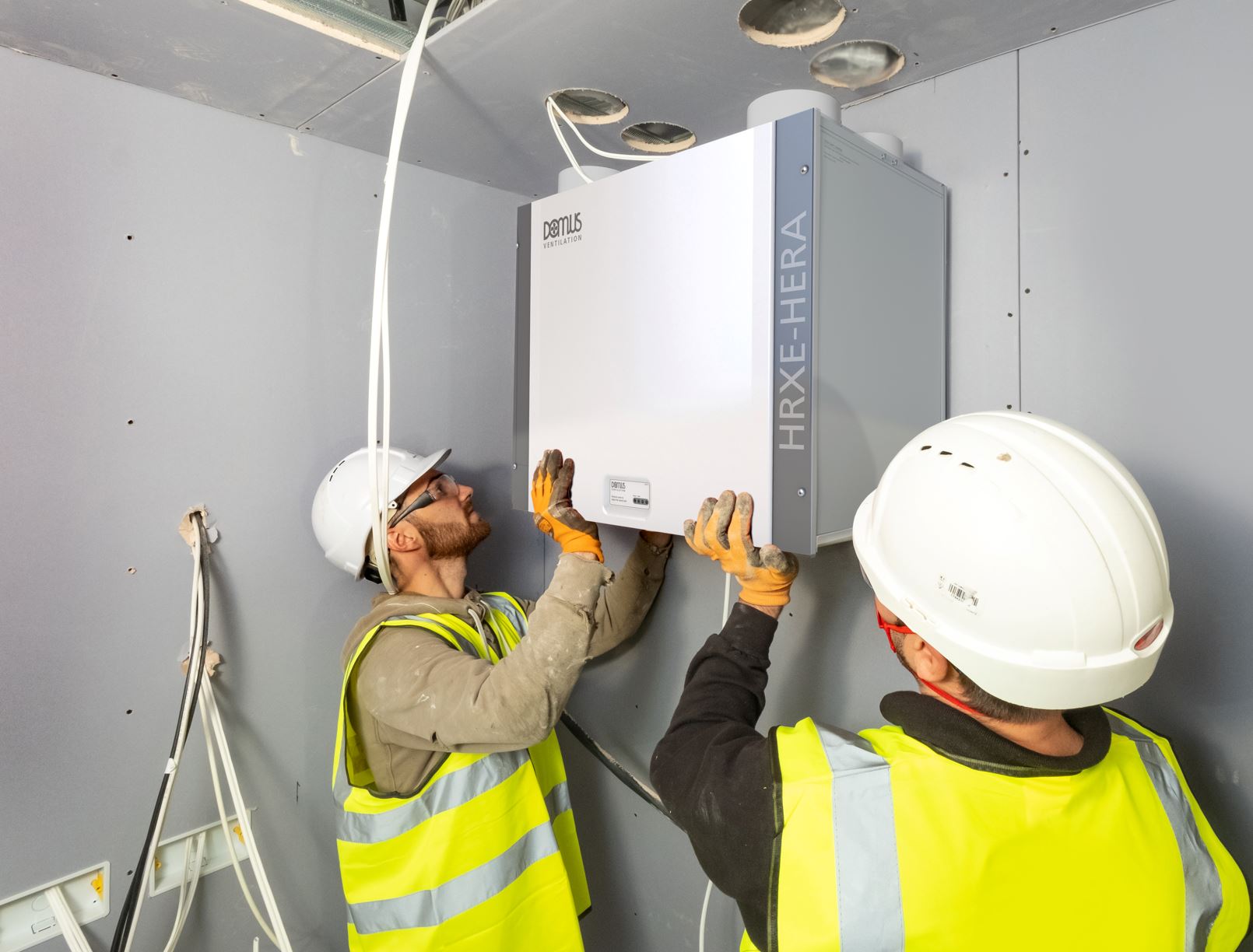 Male engineers in hardhats installing a ventilation system